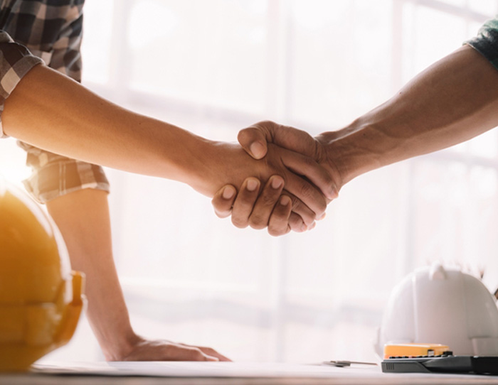 Two people shaking hands over table - Workers Compensation Services